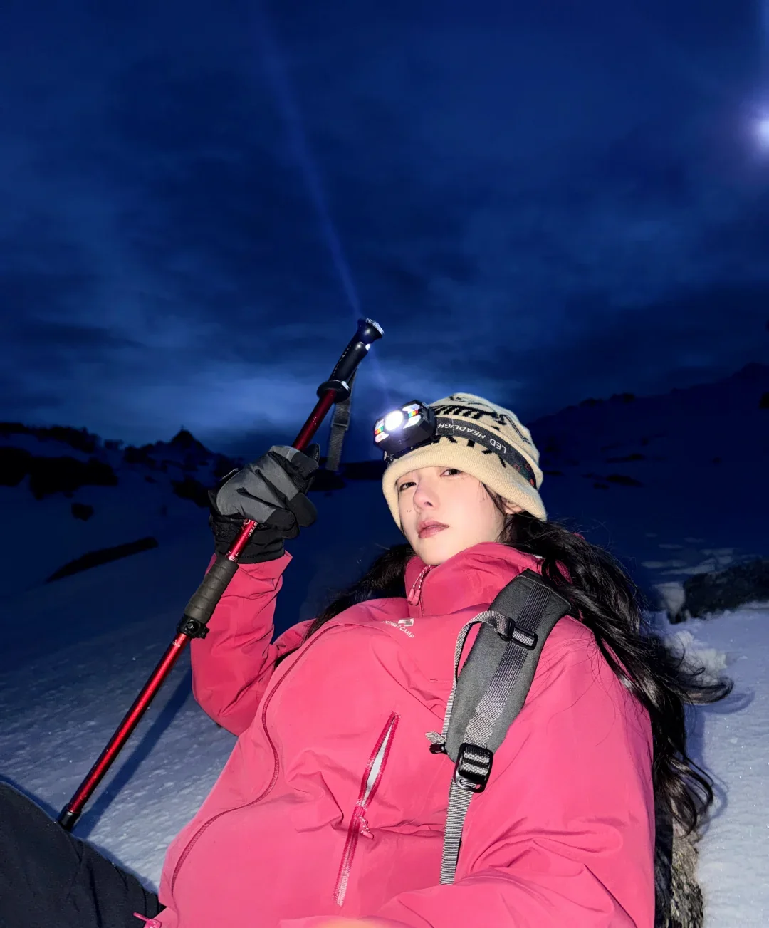 Photo of a mountain hiker in a pink jacket beneath a blue evening sky — illustrative example.