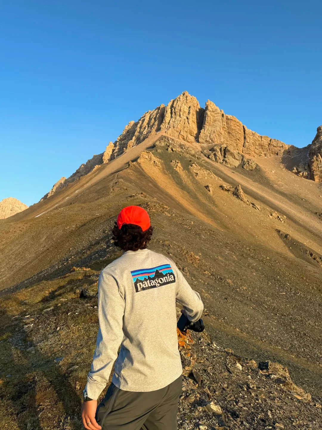 Photo of a hiker in a red cap facing golden mountain peaks — illustrative example.